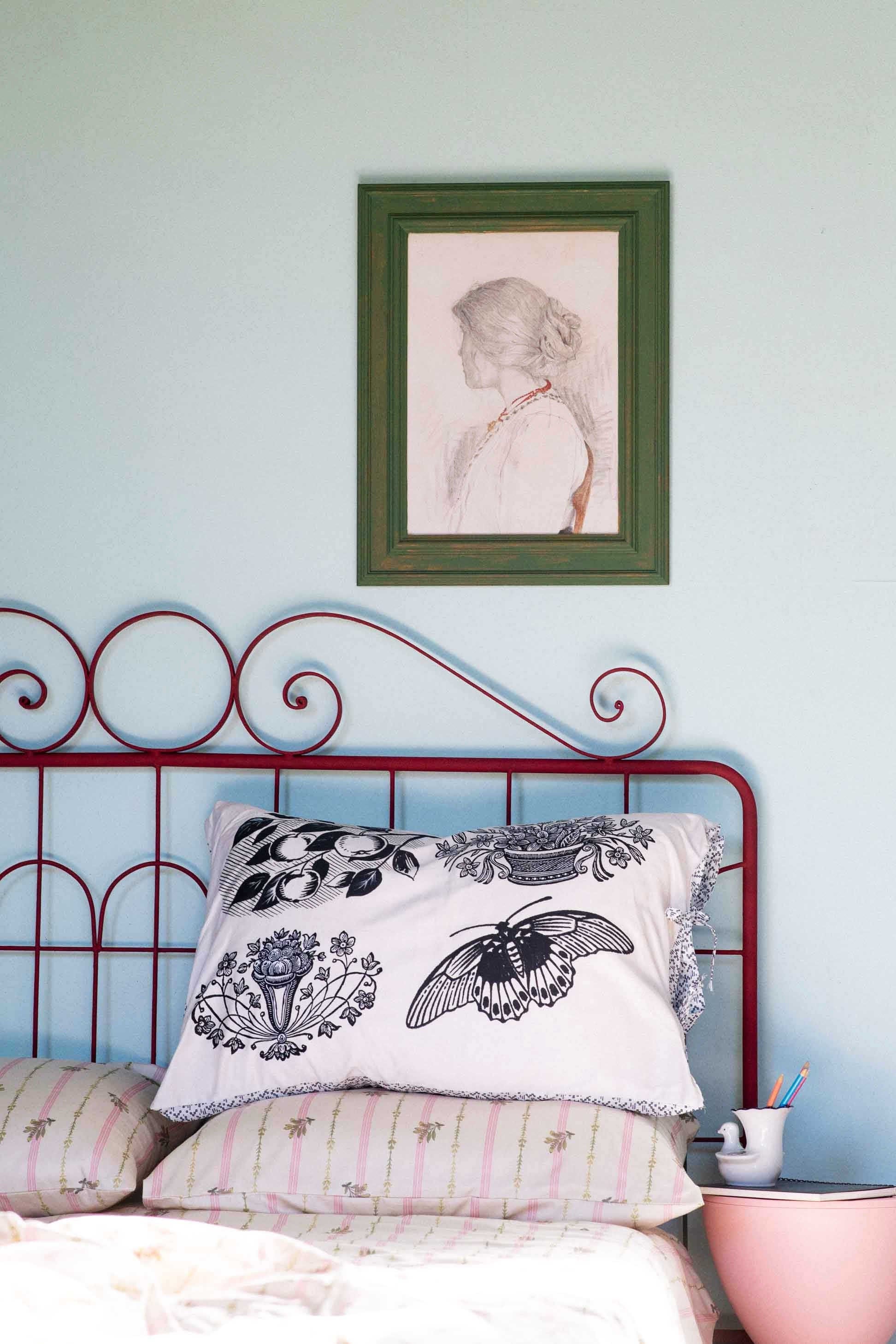 Woodcut Idony art print above bed with decorative pillows.