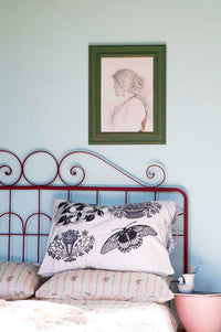 Woodcut Idony art print above bed with decorative pillows.