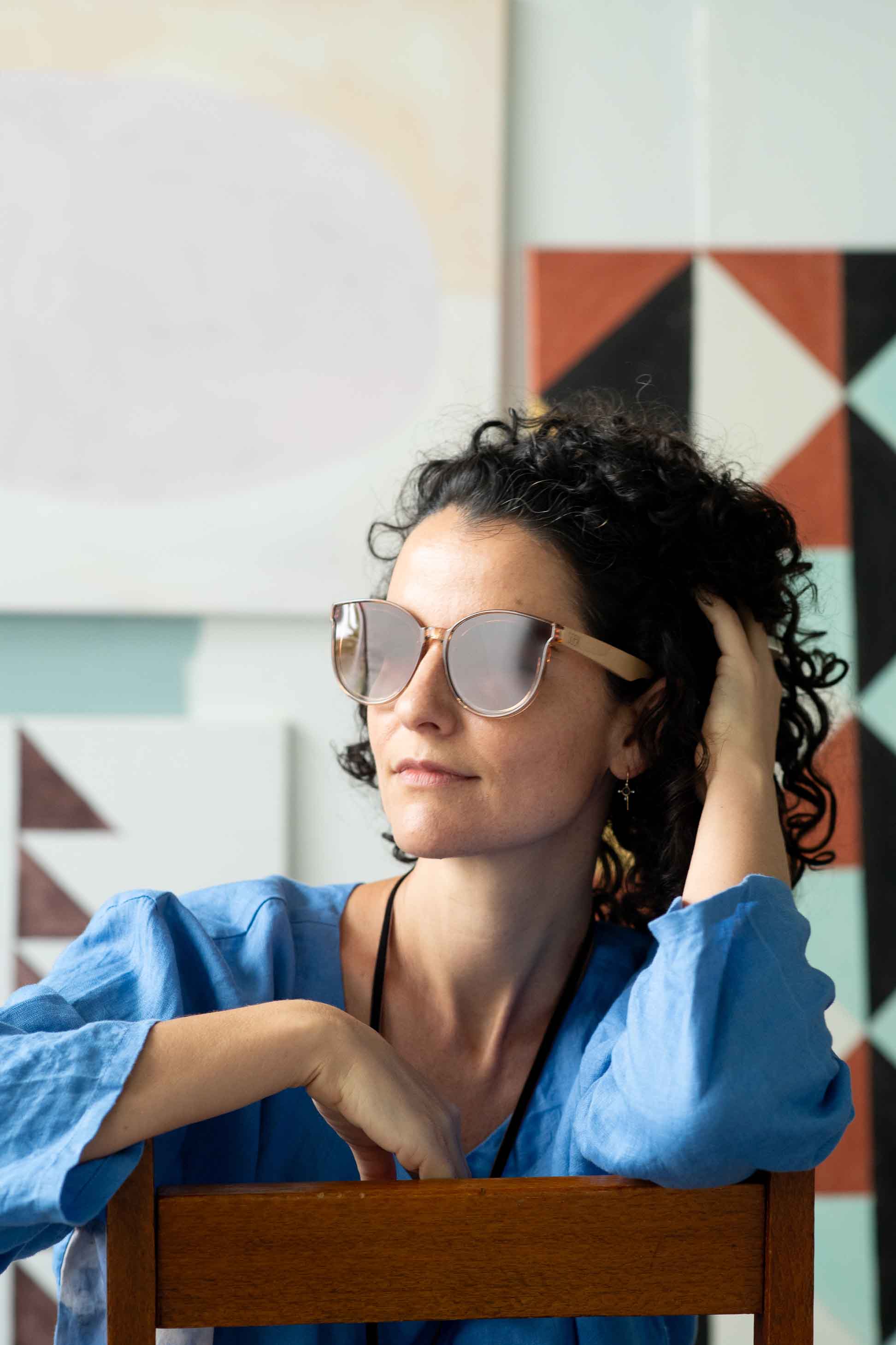 Bella Champagne Fara wearing sunglasses, portrait with clouds background.