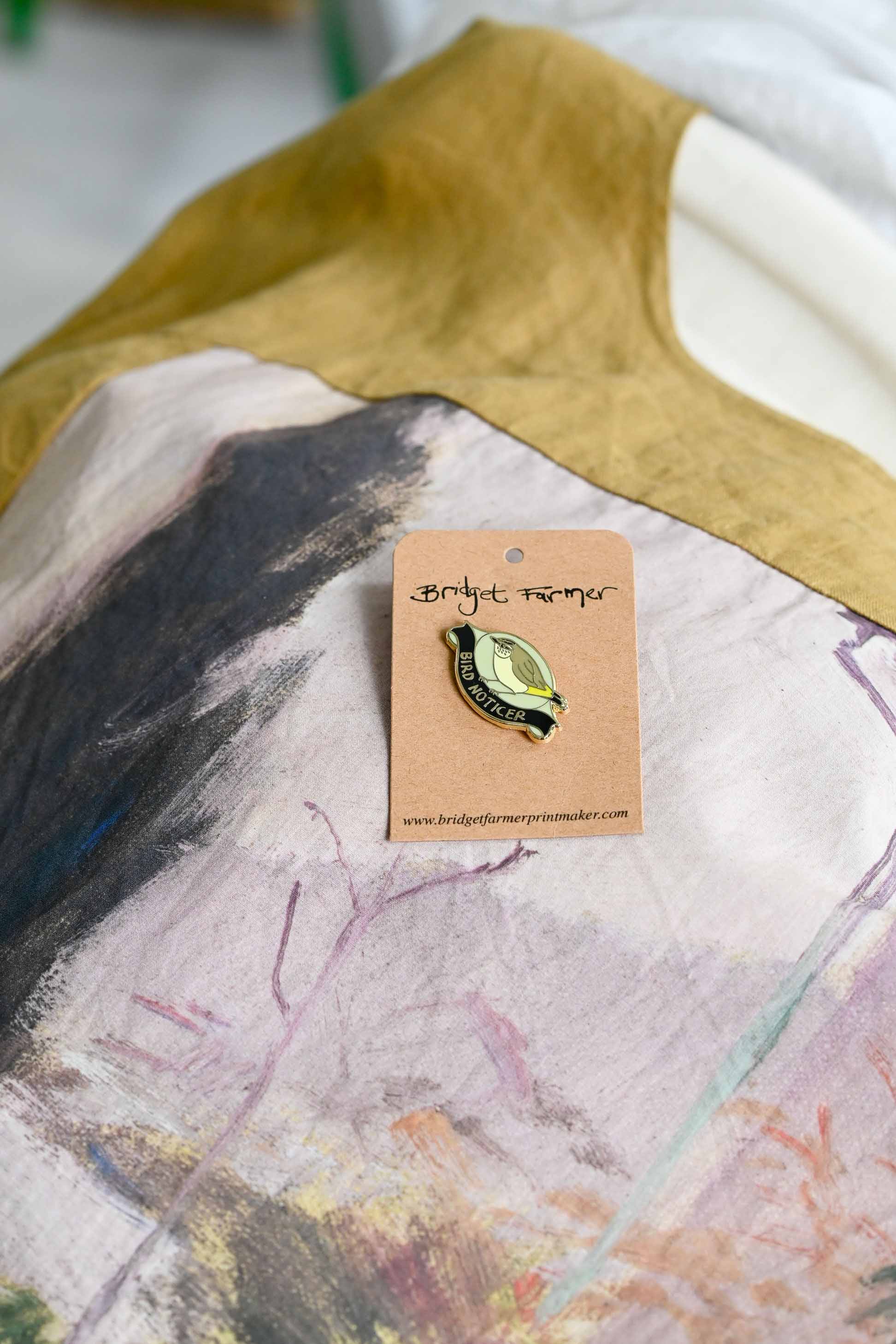 Bird Noticer pin on abstract patterned fabric