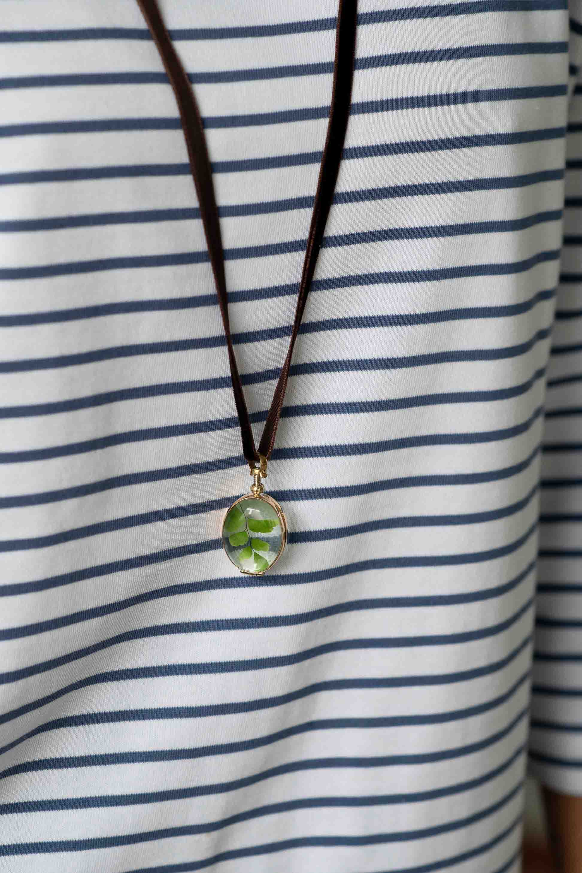 Oval crystal locket necklace on striped shirt