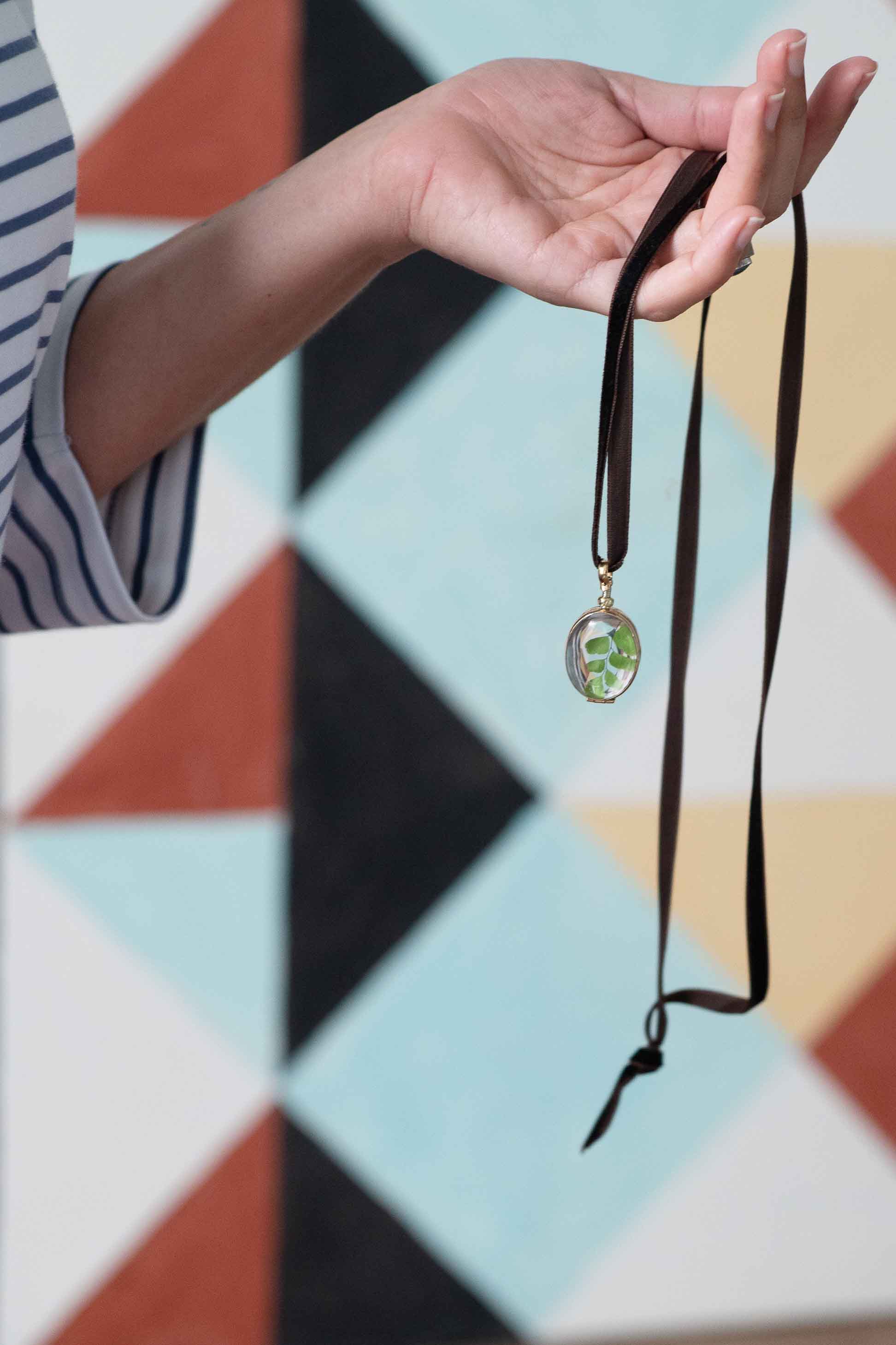 Oval crystal locket necklace held in hand