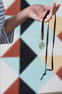 Oval crystal locket necklace held in hand