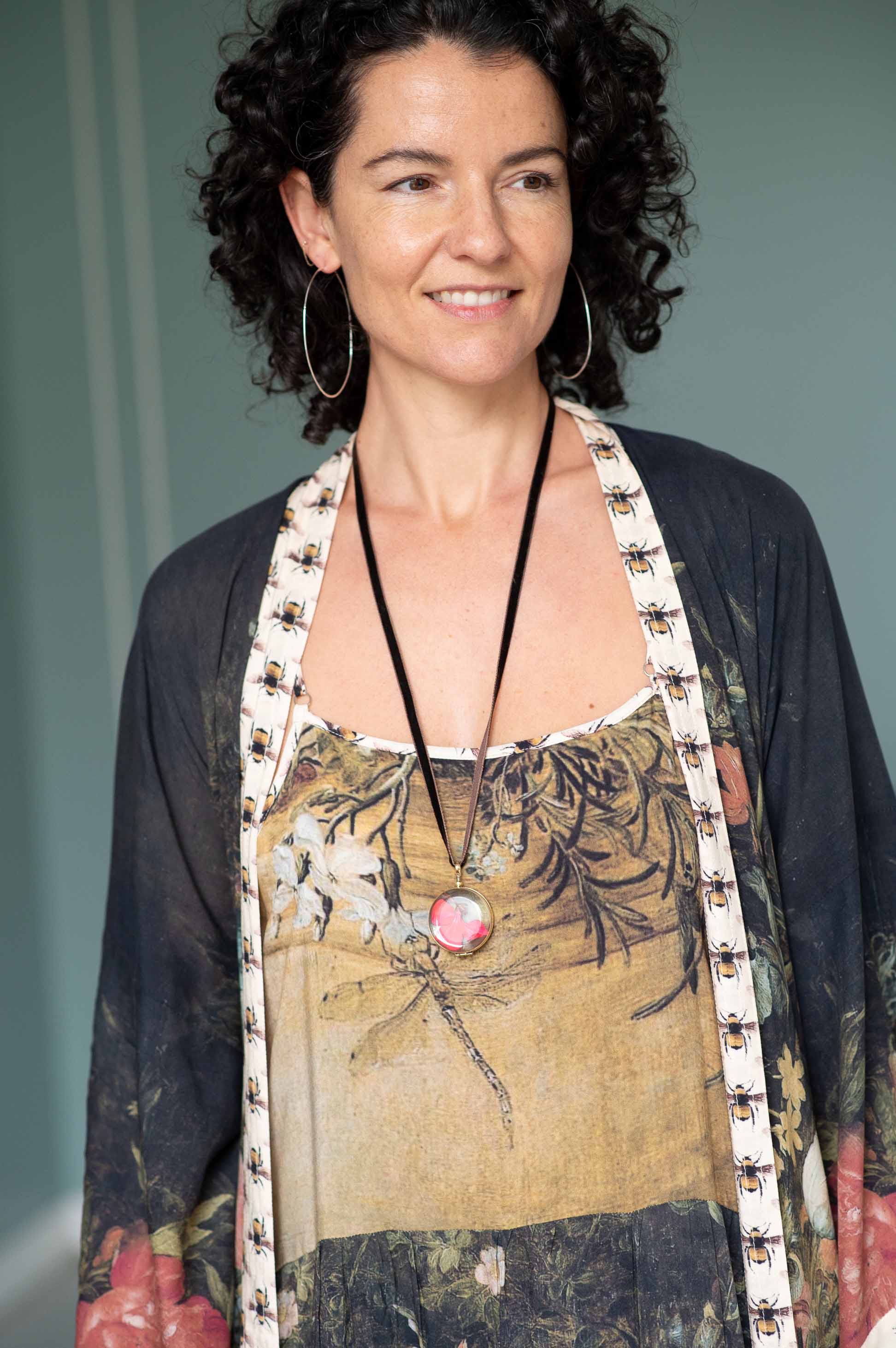Woman wearing crystal locket, silver hoops & floral duster