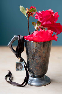 Crystal locket with portrait, red flowers in antique silver vase