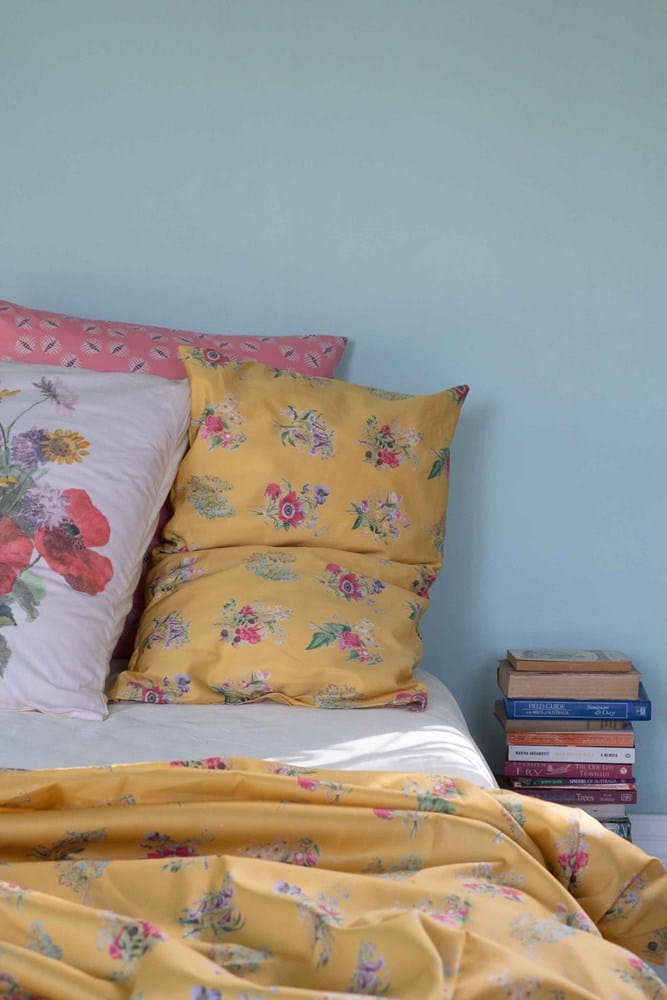 Floral bedding with yellow pillows and books