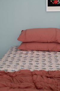 Bedroom with pink bedding and patterned sheets.