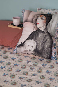 Art Deco pillow with woman and dog on floral bedsheets