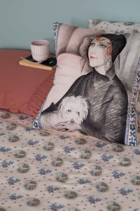 Art Deco pillow with woman and dog on floral bedsheets