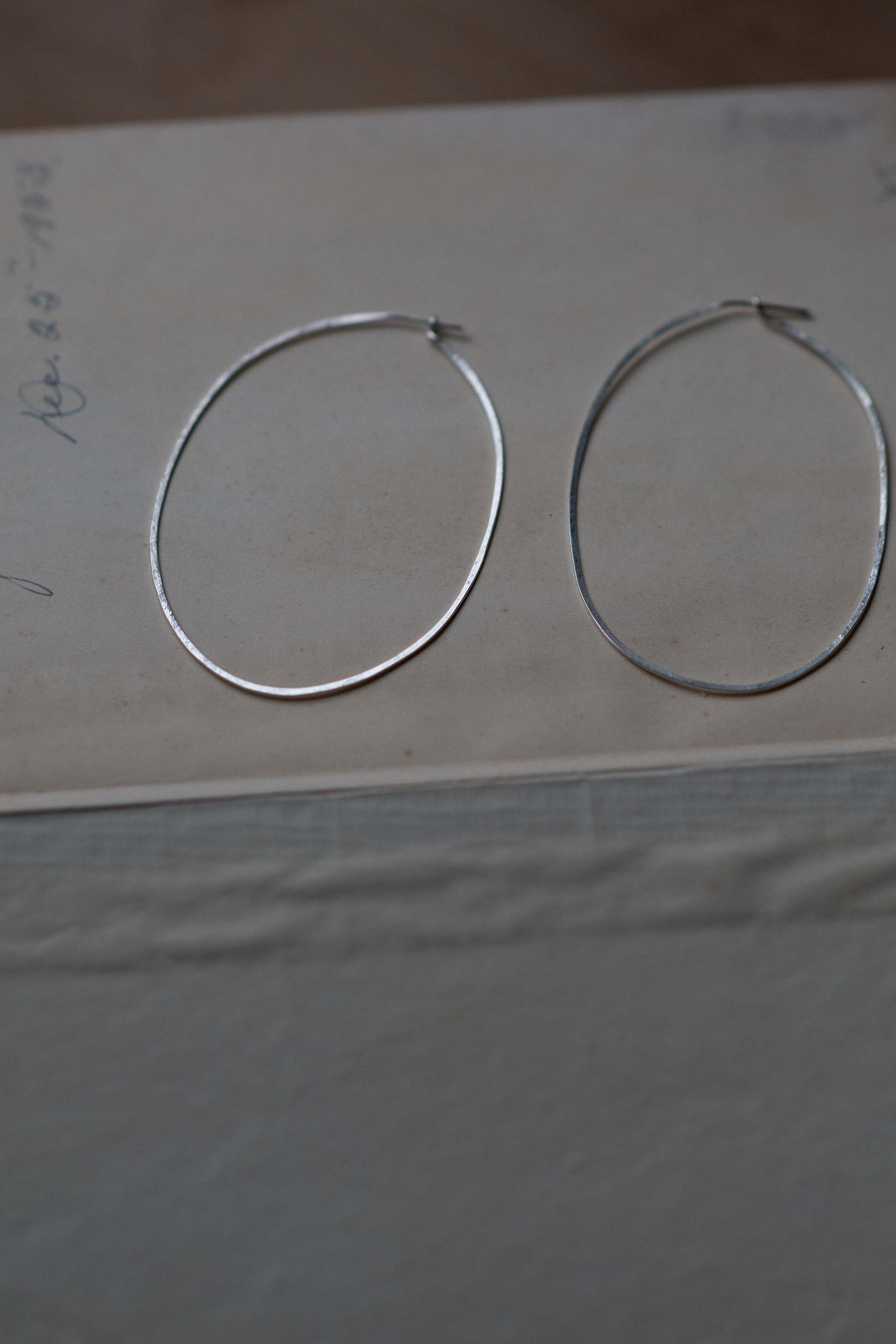 Silver hoop earrings on a neutral surface