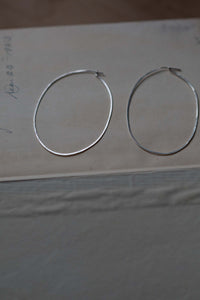 Silver hoop earrings on a neutral surface