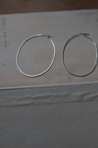 Silver hoop earrings on a neutral surface