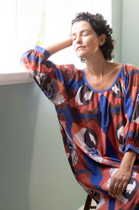 Woman in patterned dress by window