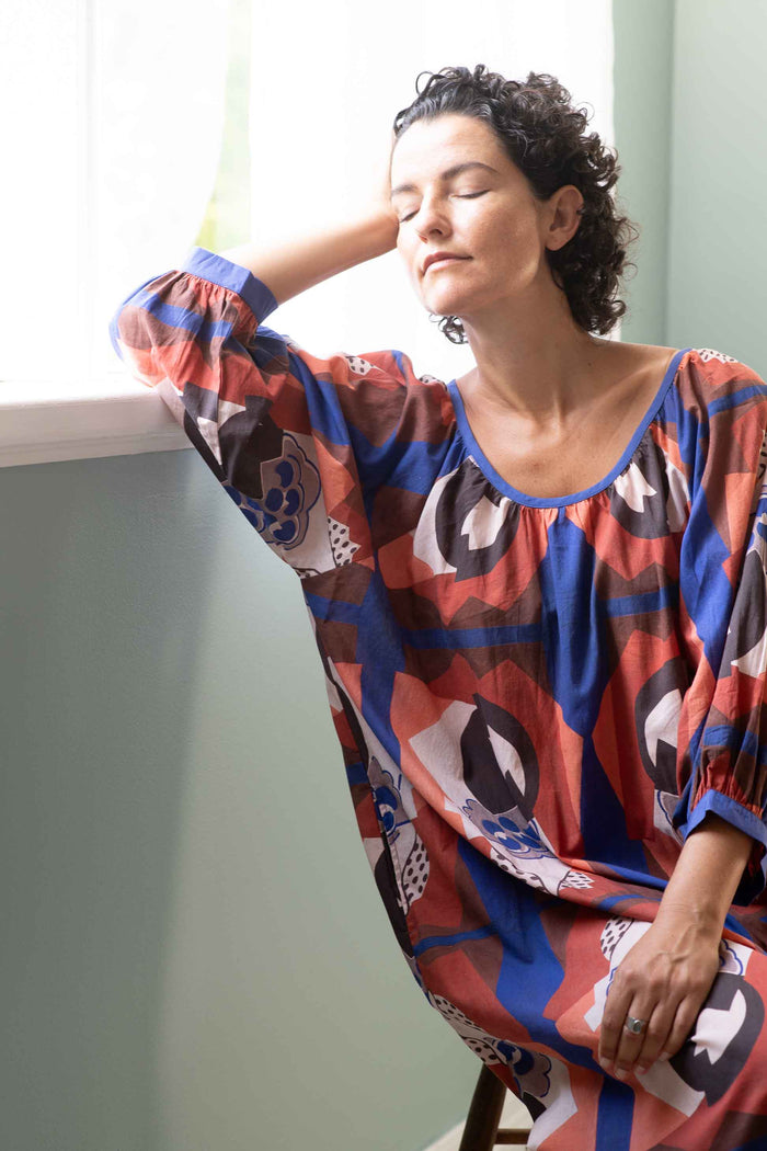Woman in patterned dress by window