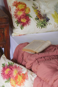 Horticole Rosette Quilt pillowcase set with floral print on bed.