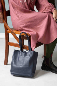 Woman in dress with navy tote and green tights