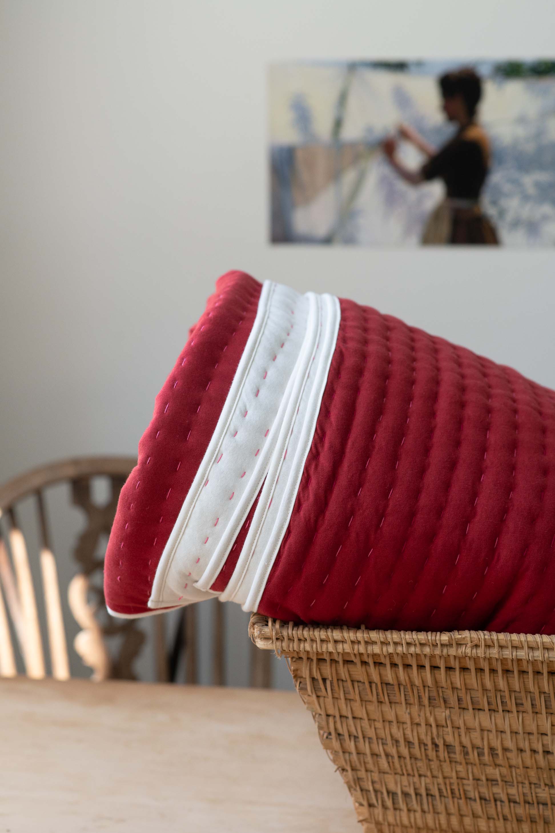 Garnet Kantha quilt with white trim in basket