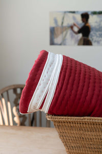 Garnet Kantha quilt with white trim in basket