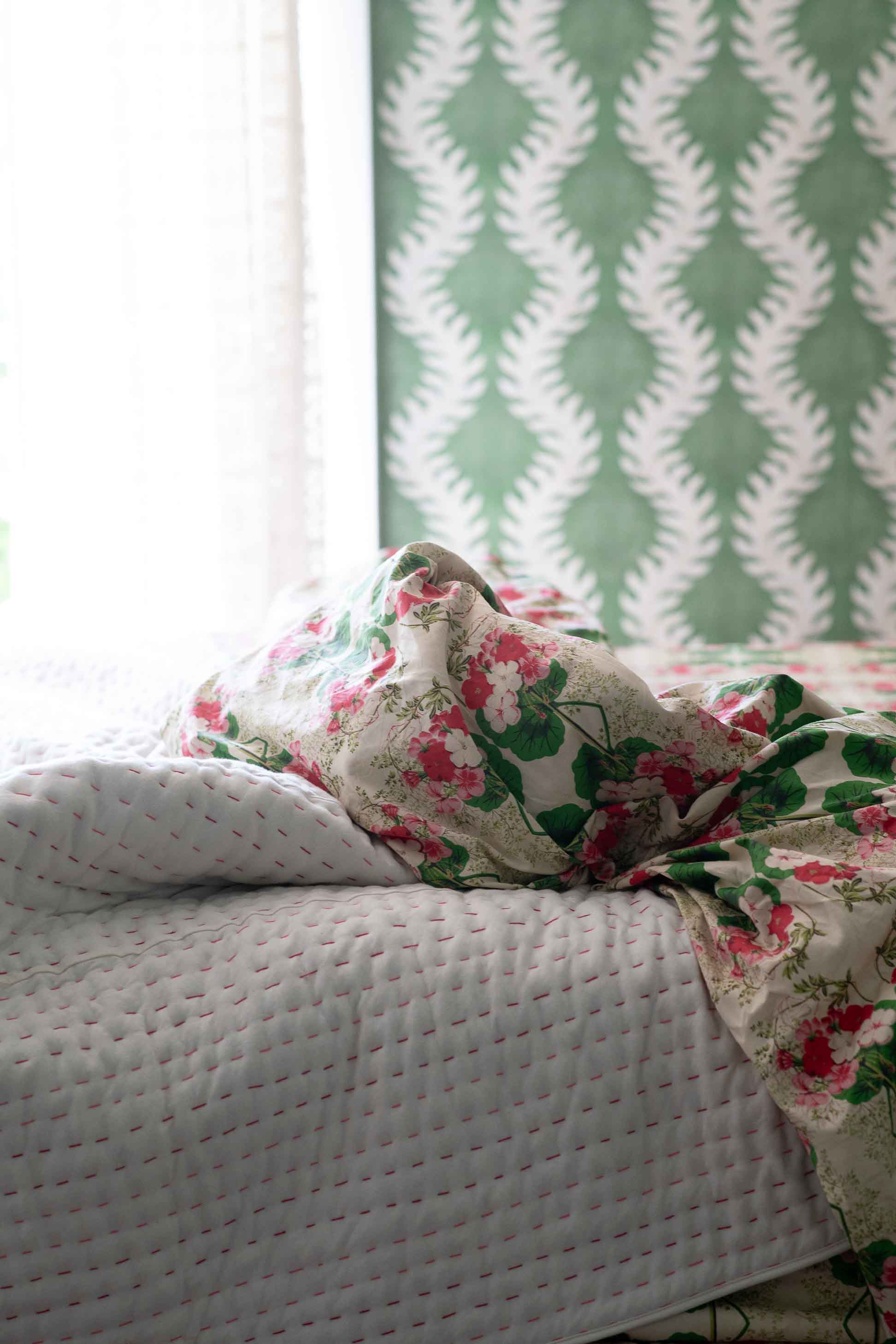 Kantha quilt & floral pelargonium sheets on bed
