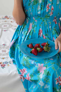 Katy Bluesette in blue dress holding plate of strawberries