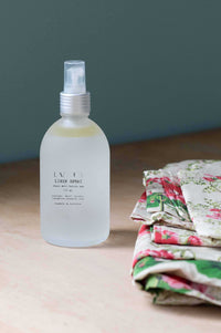Lemongrass linen spray bottle next to floral fabric