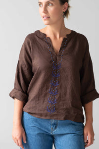 Brown top with blue embroidery and jeans