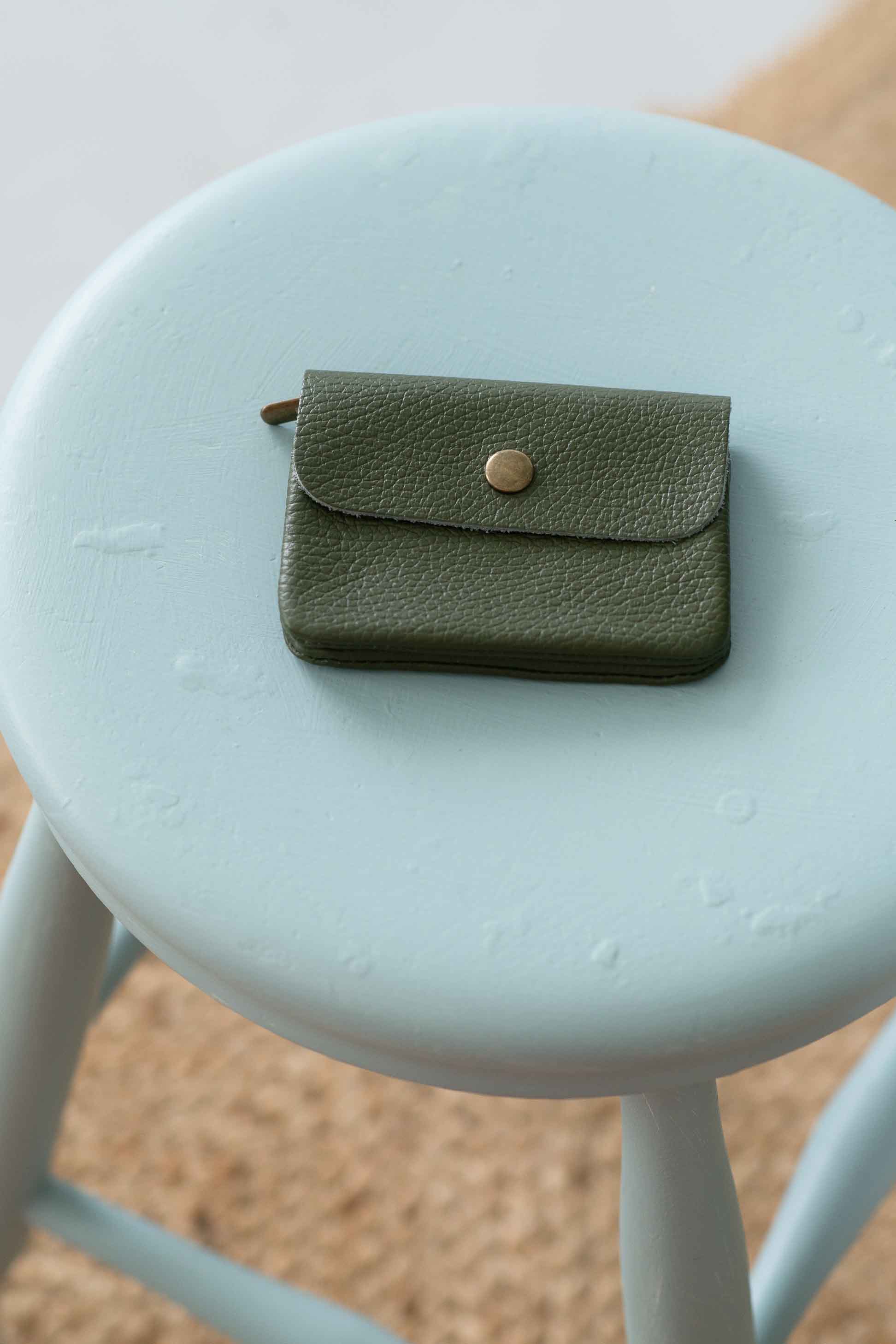 Moss green leather coin purse on stool