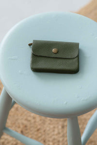 Moss green leather coin purse on stool