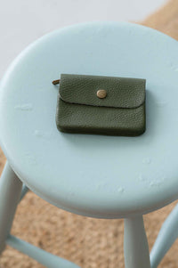 Moss green leather coin purse on stool