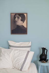 Portrait of Maria LaBelle on blue wall with pillows and vase