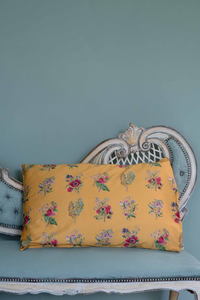 Summerland Pillowcase with floral print on a teal chaise.