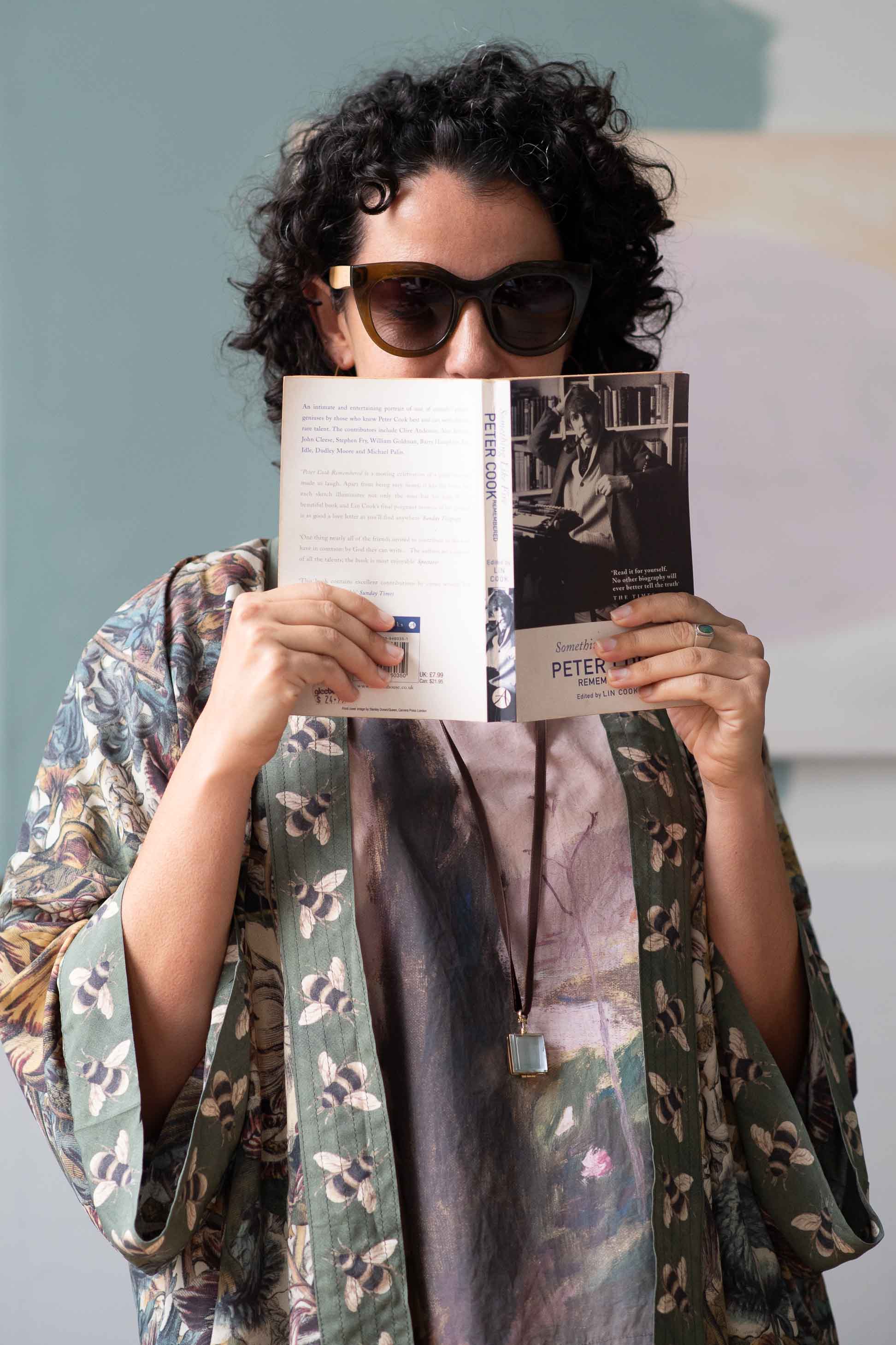 Woman in kimono reading Peter book, wearing sunglasses.