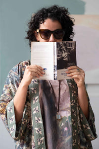 Woman in kimono reading Peter book, wearing sunglasses.
