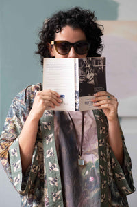 Woman in kimono reading Peter book, wearing sunglasses.