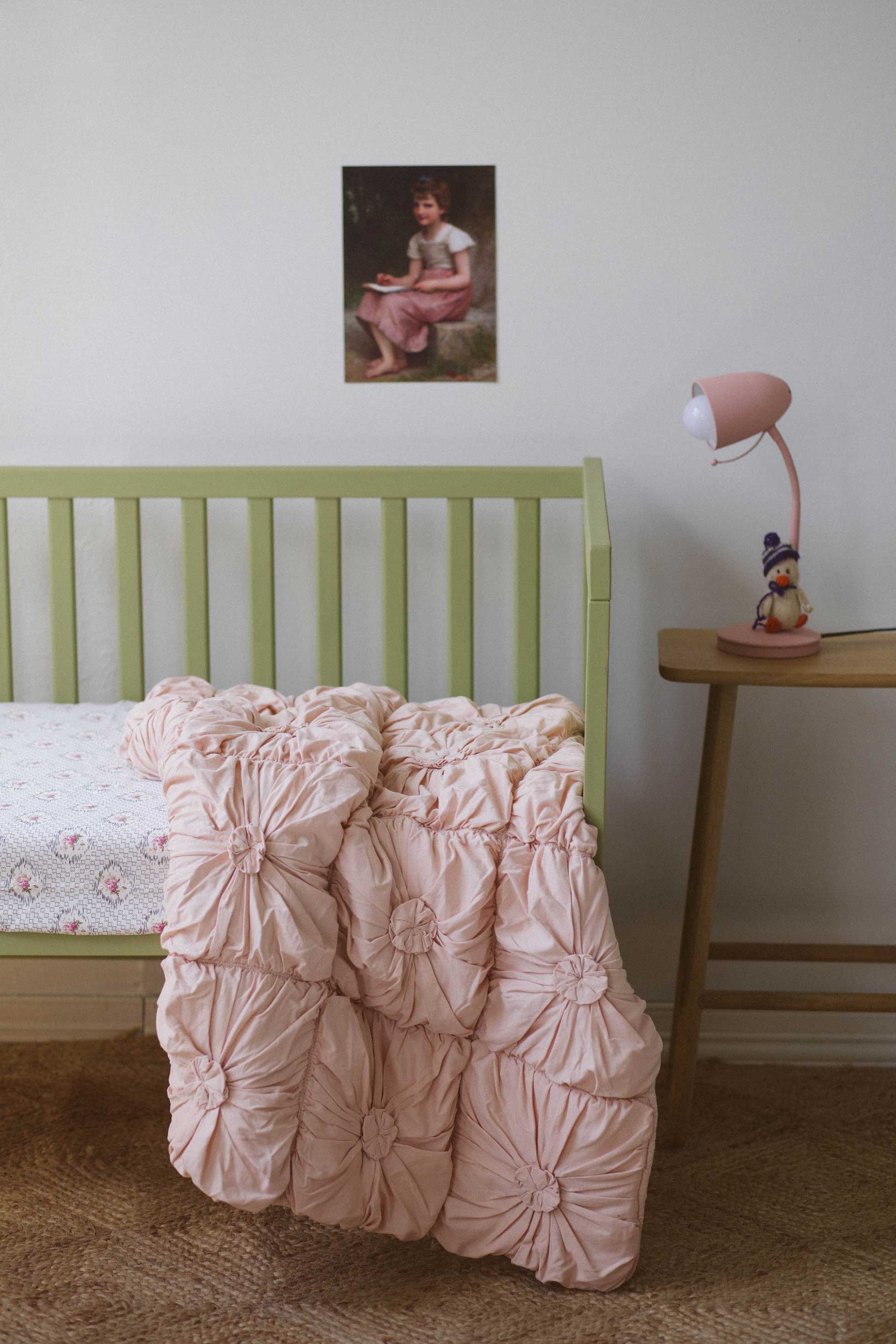 Tuscan pink cot quilt with art print in a child's bedroom.