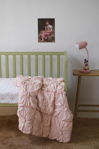 Tuscan pink cot quilt with art print in a child's bedroom.