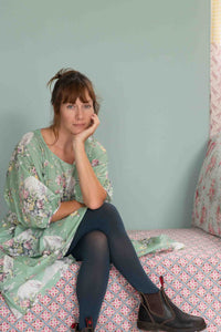 Woman in blue tights, Faith Newlyn, floral top, seated