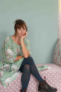 Woman in blue tights, Faith Newlyn, floral top, seated