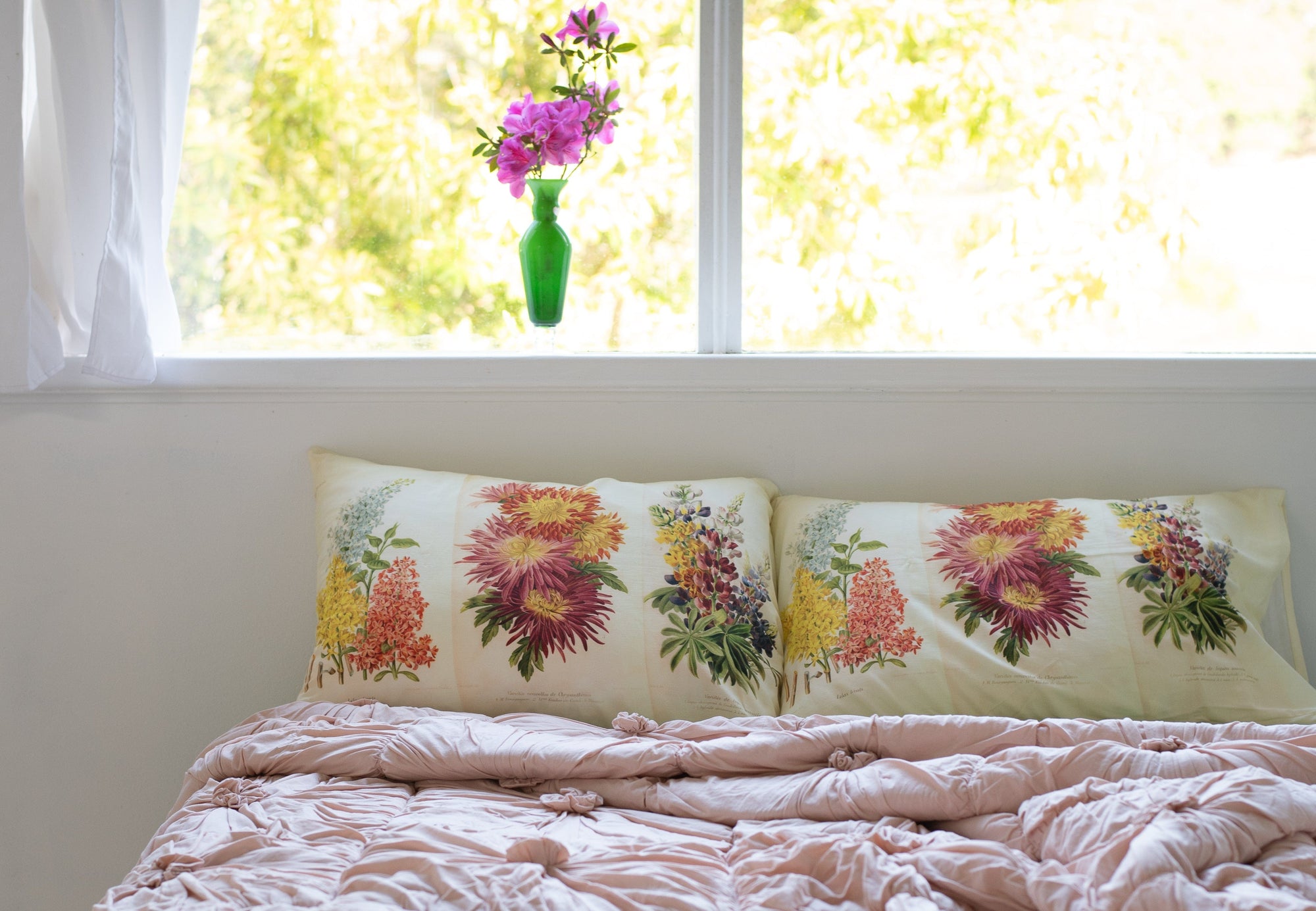 Floral pillows and azalea flowers by window.