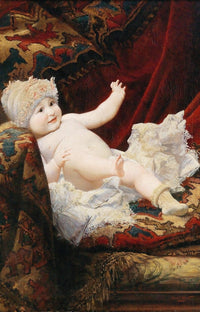 Baby wearing a fur hat and socks, lying on a decorated cushion.