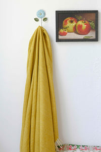 Mustard blanket on wall hook with apple art print.